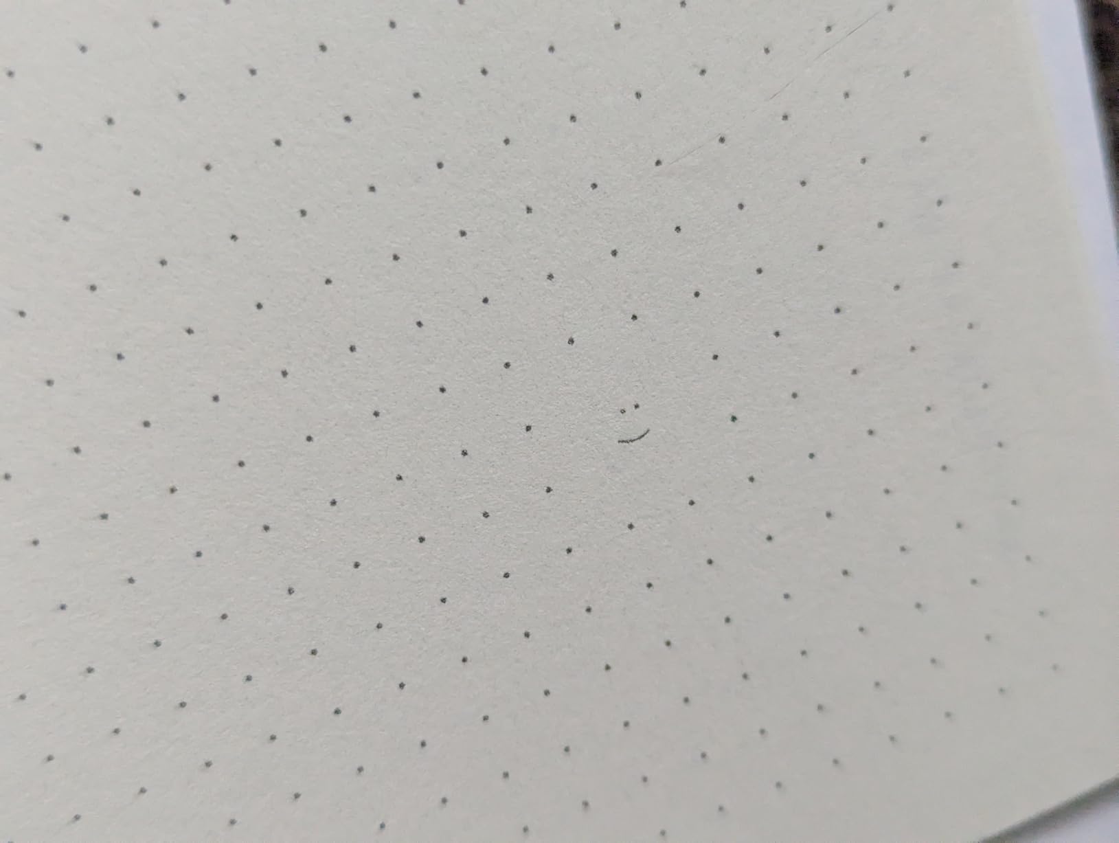 Dot grid page with a tiny penciled smiley face